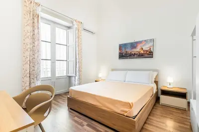 a bedroom with a bed and a desk and a window at GuestHost - Central Station Modern Apartment with Balconies x8 in Palermo