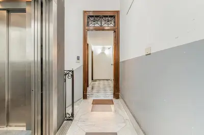 a hallway with white walls and a wooden door at GuestHost - Central Station Modern Apartment with Balconies x8 in Palermo