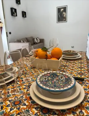 a table with plates and a bowl of oranges on it at Sicily guest house 2 in Palermo