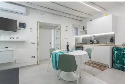 a white kitchen with a table and chairs at Apartment al Vicolo 27 in Palermo