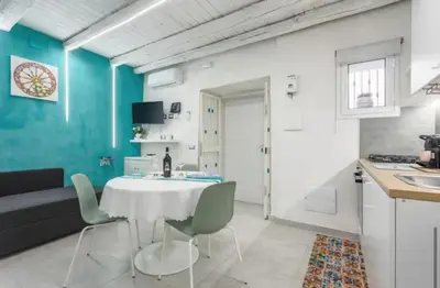 a kitchen and dining room with a white table and chairs at Apartment al Vicolo 27 in Palermo