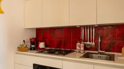 a kitchen with a sink and red tile on the wall at Aerial House in Palermo