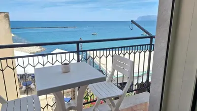 a white table and chairs on a balcony with the ocean at Umàri Rooms in Castellammare del Golfo