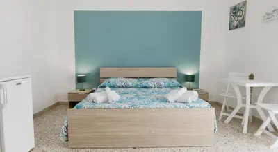 a bedroom with a bed with blue sheets and white pillows at Umàri Rooms in Castellammare del Golfo