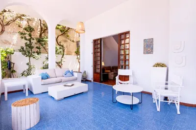 a living room with blue floors and white furniture at Vista Mare by DomuSicily in Cinisi