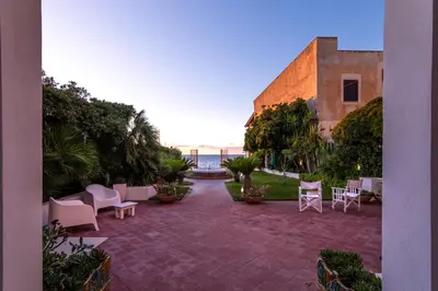 a patio with chairs and tables and a building at Vista Mare by DomuSicily in Cinisi