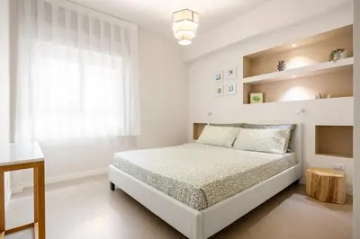 a white bedroom with a bed and a window at Maison169 in Palermo