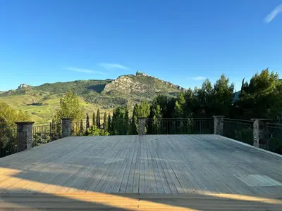 a large wooden deck with mountains in the background at Le Case di Cardellino - AgriSpa in Sclafani