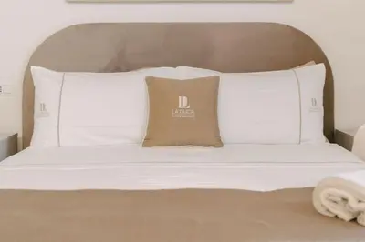 a bed with white sheets and pillows on it at La Duca Suites & Apartments in Palermo