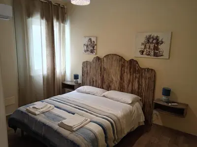 a bedroom with a large wooden bed with two towels on it at Virginia Holiday Home in Mondello
