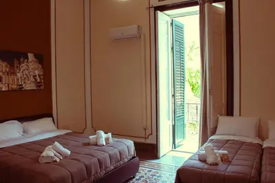 two beds sitting in a room with a window at Mizzica Rooms in Palermo