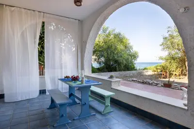 a table and a bench in a room with a window at Casa Eugenia in Santa Flavia