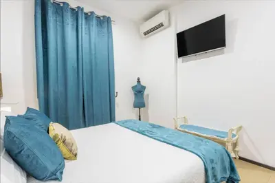 a bedroom with a bed with blue curtains and a flat screen tv at La casa di Alice in Palermo