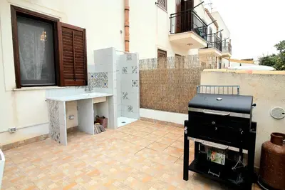 a grill on a patio with a building at Il Fico d'India in San Vito lo Capo