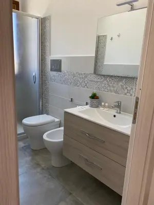 a bathroom with a sink and a toilet and a mirror at San Vito Holiday Home in San Vito lo Capo