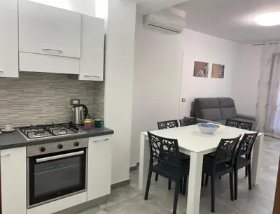 a kitchen with a stove and a table with chairs at San Vito Holiday Home in San Vito lo Capo