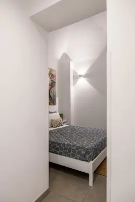 a white bedroom with a bed and a chair at Casa Azzurra Rooms e apartment in Terrasini