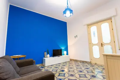 a living room with a blue wall and a couch at Pegaso 15 Home in Palermo