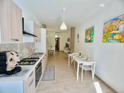 a kitchen with a stove and a table with chairs at Domus Livi in Cinisi