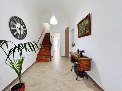 a hallway with a clock and a desk and a plant at Domus Livi in Cinisi