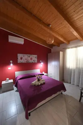 a bedroom with a purple bed and a red wall at AL Quadrifoglio in Terrasini