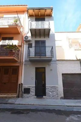 a white building with a balcony and a door at AL Quadrifoglio in Terrasini