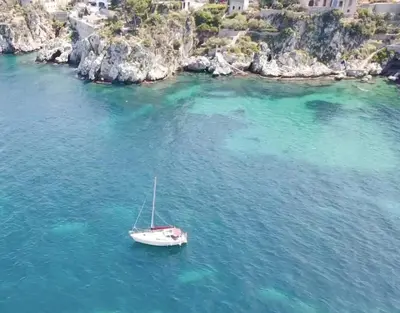 a white boat in the water near a rocky coast at Antico Casale Formica in Bagheria