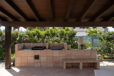 a outdoor kitchen with a bench under a pergola at VillaThomas in Campofelice di Roccella