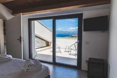 a bedroom with a sliding glass door with a view of the ocean at Tenuta Rapillo in Castellammare del Golfo