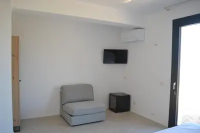 a bedroom with a chair and a tv on a wall at Tenuta Rapillo in Castellammare del Golfo