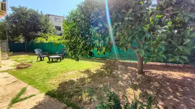 a garden with a tree and a table and chairs at Villa Triscele Holiday Home in Partinico