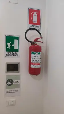 a fire extinguisher hanging on a wall with signs at Villa Triscele Holiday Home in Partinico