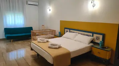a bedroom with a bed and a blue chair at Villa Triscele Holiday Home in Partinico