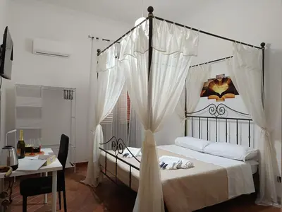a bedroom with a canopy bed with a table and a desk at B&B a casa di Peppe in Palermo