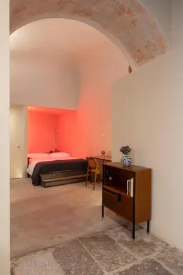 a bedroom with a bed and a table in a room at Lofterì by DomuSicily in Palermo