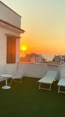 a group of chairs and tables on a balcony with the sunset at Attico con vista mozzafiato a due passi dal mare in Terrasini