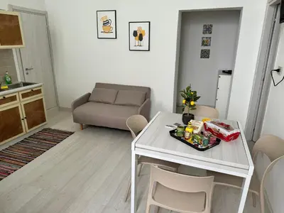 a kitchen and living room with a white table and chairs at Ballar'Home - Casa Sbriju' in Palermo