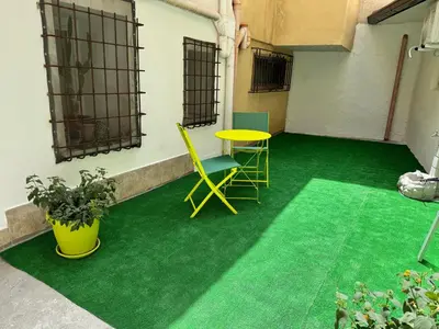 a room with a green floor and a table and chairs at Ballar'Home - Casa Sbriju' in Palermo
