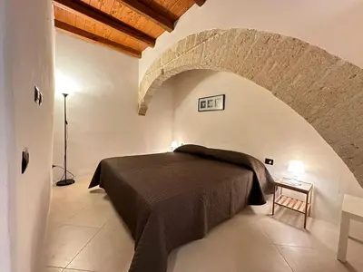 a bedroom with a bed in a stone wall at Marcantonio Suite in Castellammare del Golfo