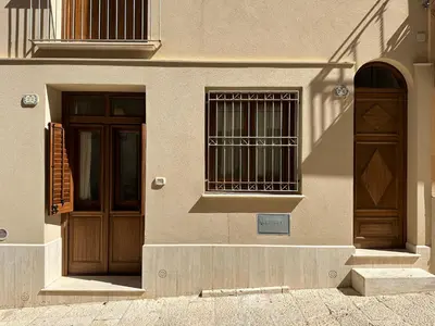 a building with two wooden doors and a window at Marcantonio Suite in Castellammare del Golfo