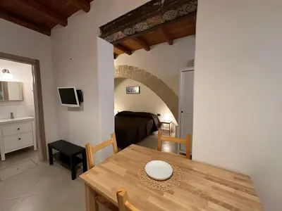 a dining room with a table and a bedroom at Marcantonio Suite in Castellammare del Golfo