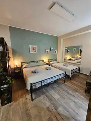 two beds in a room with green walls and wooden floors at RC SUITE Annunziata in Termini Imerese