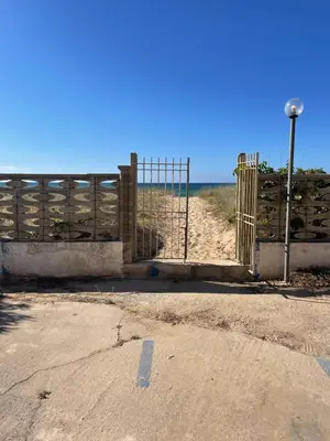 an open gate on a beach with a fence at Casa Letizia in Alcamo