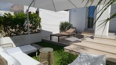 a patio with white furniture and an umbrella at BellaVista in Cinisi