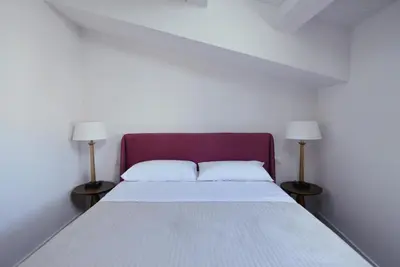 a bed in a white room with two lamps at Maciuni Apartment in Palermo
