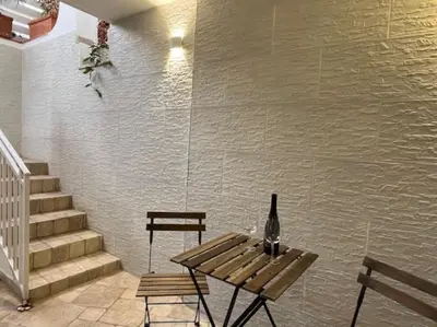 a bottle of wine sitting on a table next to a wall at Full Semi-Garden apartment in Villa at Mondello in Palermo