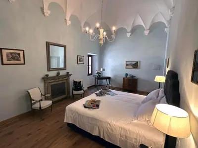 a bedroom with a large bed and a chandelier at Abbazia Santa Maria del Bosco in Contessa Entellina