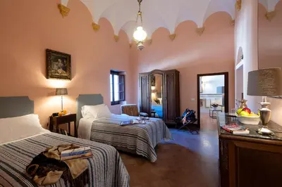 a bedroom with two beds and a living room at Abbazia Santa Maria del Bosco in Contessa Entellina