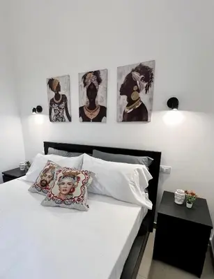 a bedroom with a white bed with four pictures on the wall at Il Moro di Ballarò - Palermo Rooms in Palermo