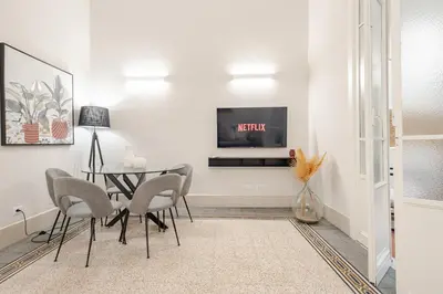 a dining room with a table and a tv on a wall at Zahir Suite Apartment in Palermo